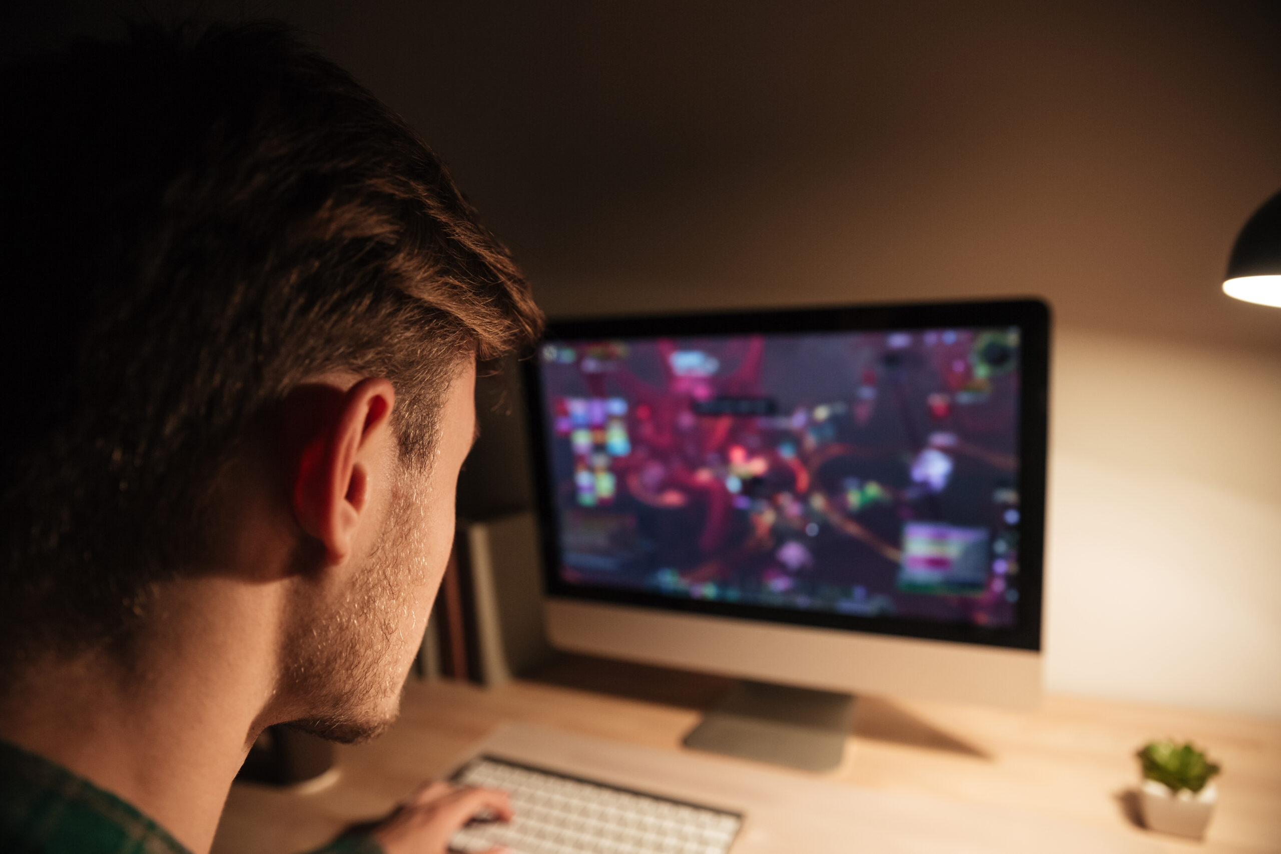 Man playing computer games at table in the evening